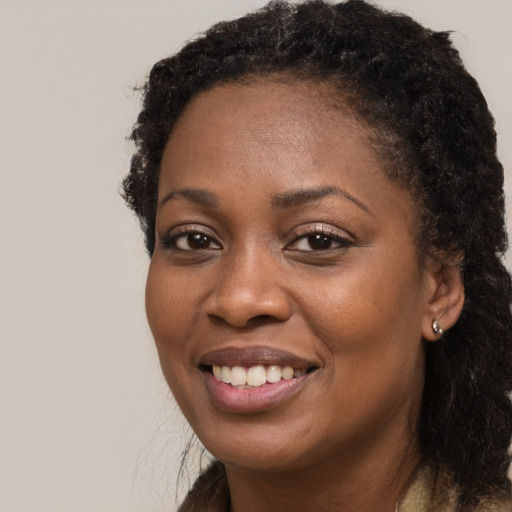 Joyful black young-adult female with long  brown hair and brown eyes