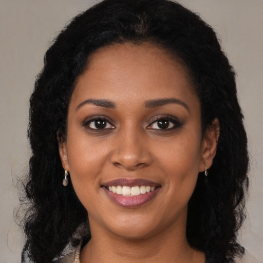 Joyful black young-adult female with long  brown hair and brown eyes