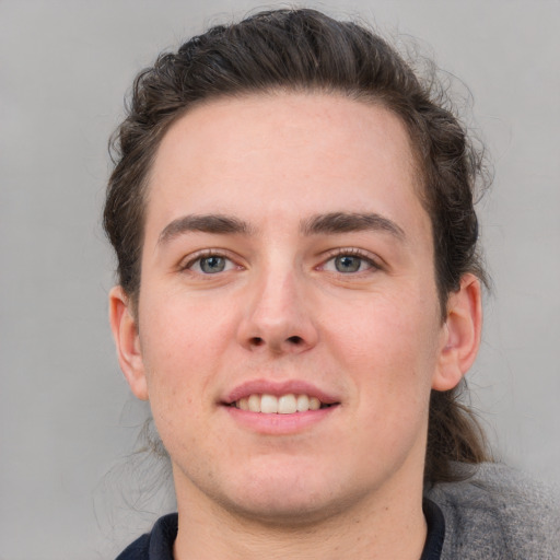 Joyful white young-adult male with medium  brown hair and grey eyes