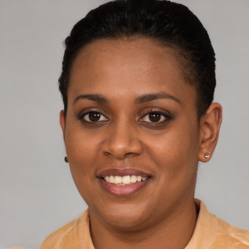 Joyful black young-adult female with short  black hair and brown eyes