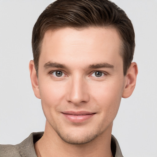 Joyful white young-adult male with short  brown hair and grey eyes