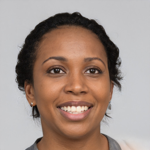 Joyful black young-adult female with long  black hair and brown eyes
