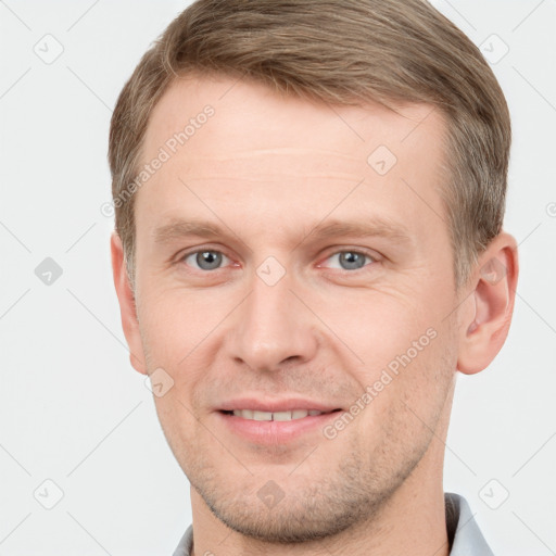 Joyful white young-adult male with short  brown hair and grey eyes