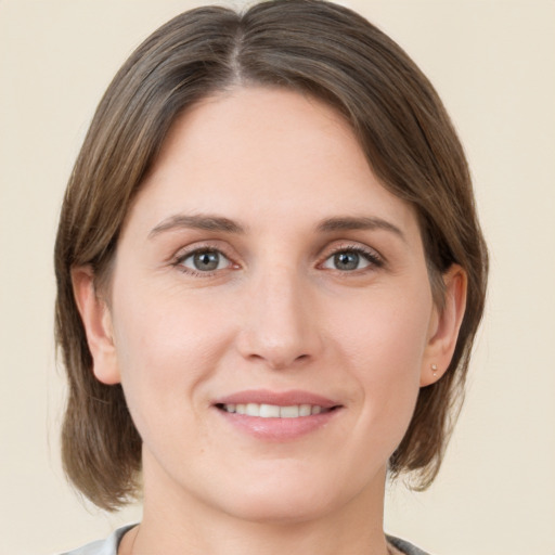 Joyful white young-adult female with medium  brown hair and grey eyes