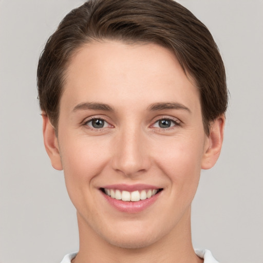 Joyful white young-adult female with short  brown hair and grey eyes