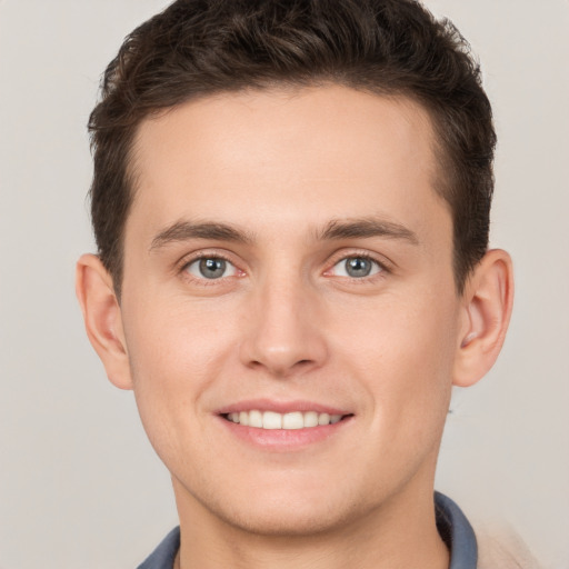 Joyful white young-adult male with short  brown hair and grey eyes