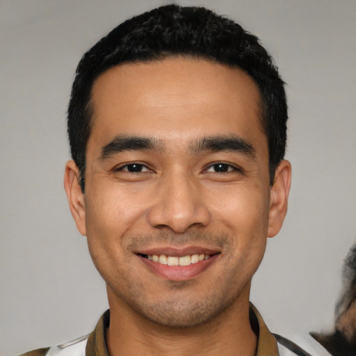 Joyful latino young-adult male with short  black hair and brown eyes