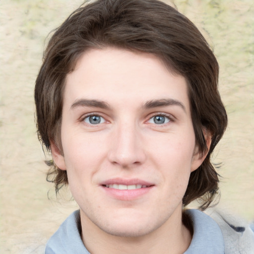 Joyful white young-adult male with medium  brown hair and grey eyes