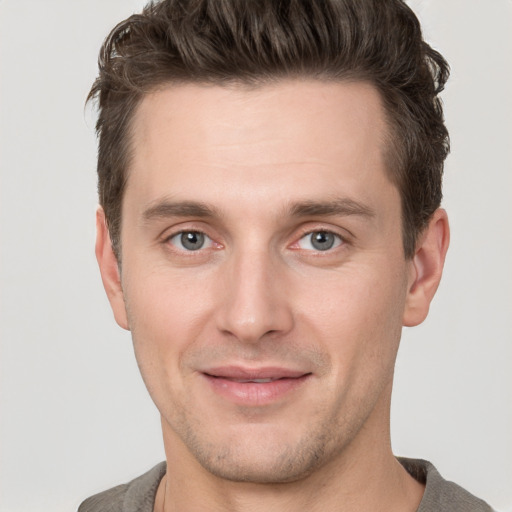 Joyful white young-adult male with short  brown hair and grey eyes