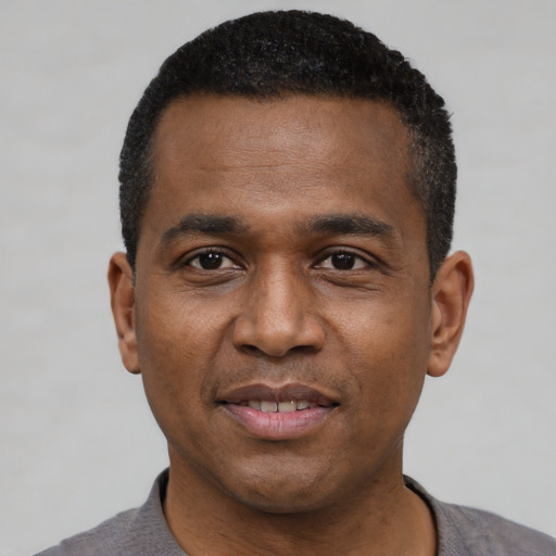 Joyful black young-adult male with short  black hair and brown eyes