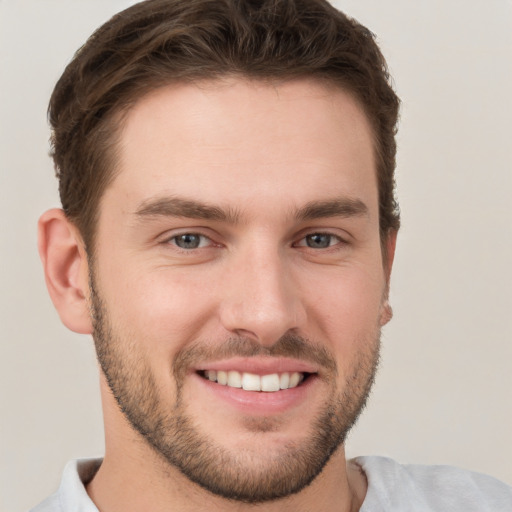 Joyful white young-adult male with short  brown hair and grey eyes