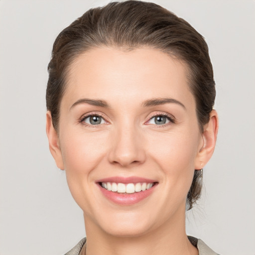 Joyful white young-adult female with medium  brown hair and grey eyes