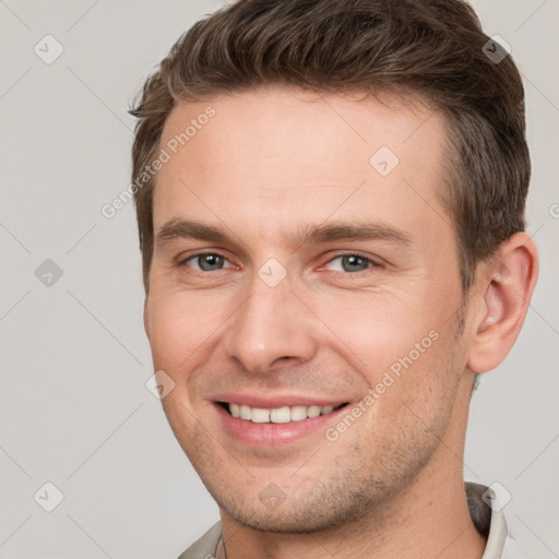 Joyful white young-adult male with short  brown hair and grey eyes