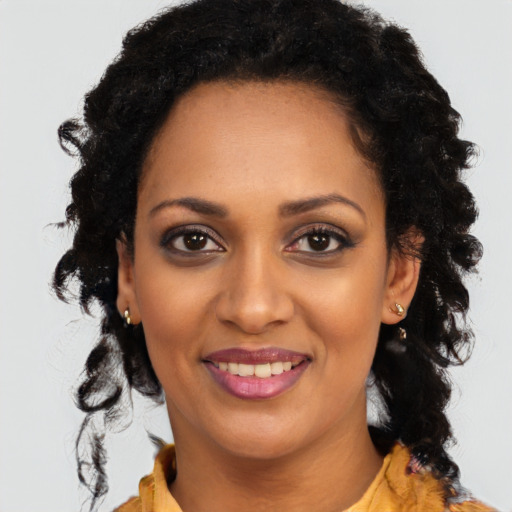 Joyful black young-adult female with long  black hair and brown eyes