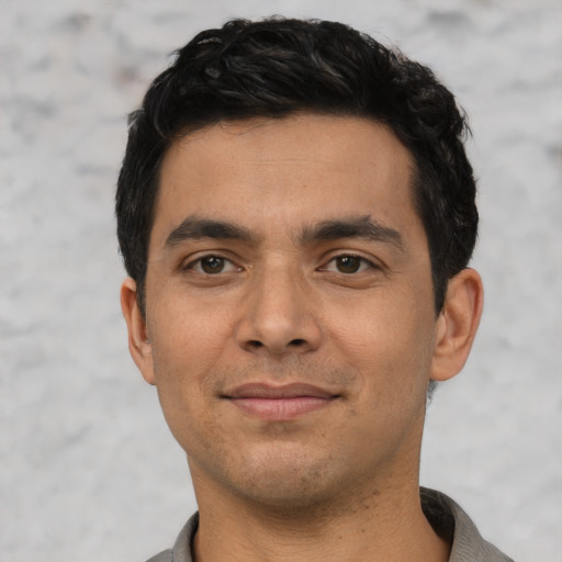 Joyful latino young-adult male with short  black hair and brown eyes