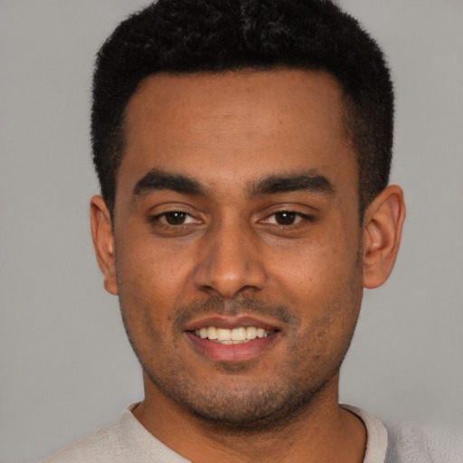 Joyful black young-adult male with short  black hair and brown eyes