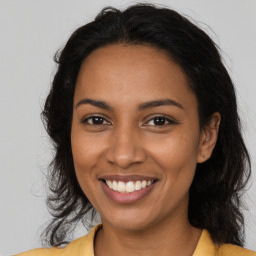 Joyful black young-adult female with long  brown hair and brown eyes