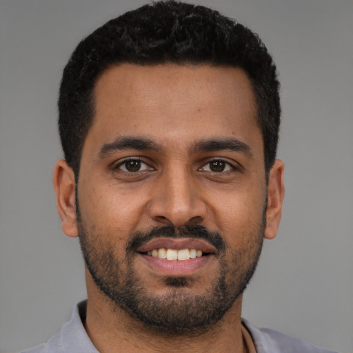 Joyful black young-adult male with short  black hair and brown eyes