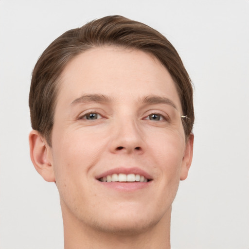 Joyful white young-adult male with short  brown hair and grey eyes