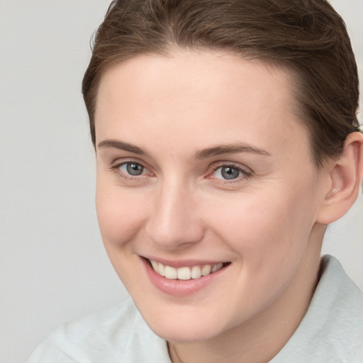 Joyful white young-adult female with short  brown hair and grey eyes