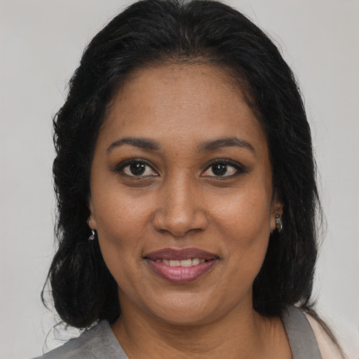 Joyful black adult female with long  brown hair and brown eyes