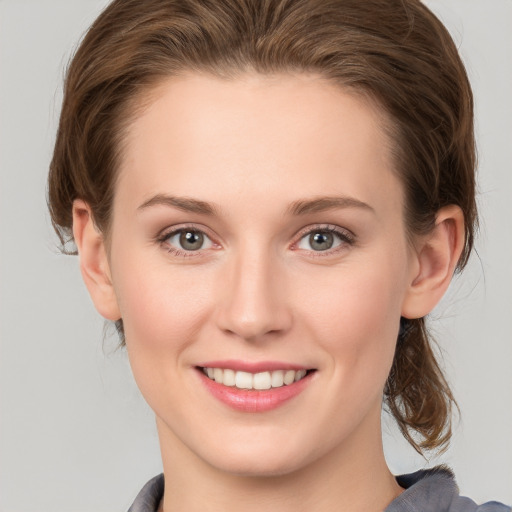 Joyful white young-adult female with medium  brown hair and grey eyes