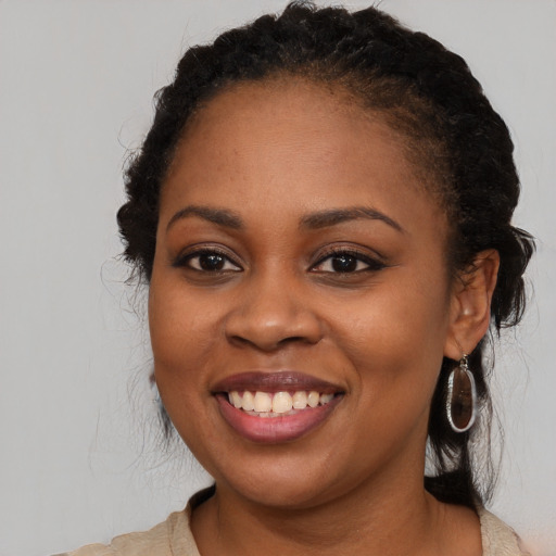 Joyful black young-adult female with long  brown hair and brown eyes