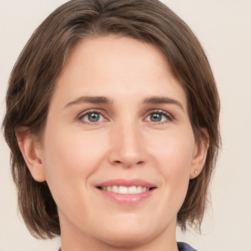 Joyful white young-adult female with medium  brown hair and grey eyes