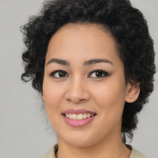 Joyful black young-adult female with long  brown hair and brown eyes