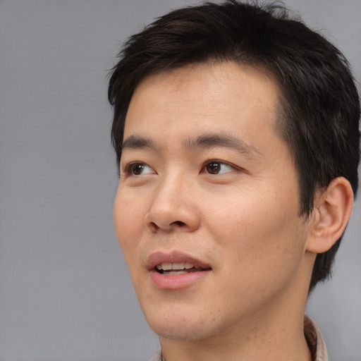 Joyful asian young-adult male with short  brown hair and brown eyes