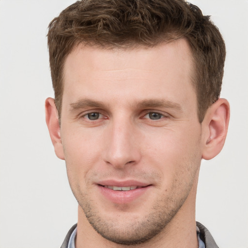 Joyful white young-adult male with short  brown hair and grey eyes