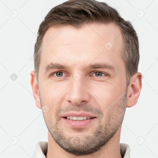 Joyful white young-adult male with short  brown hair and grey eyes