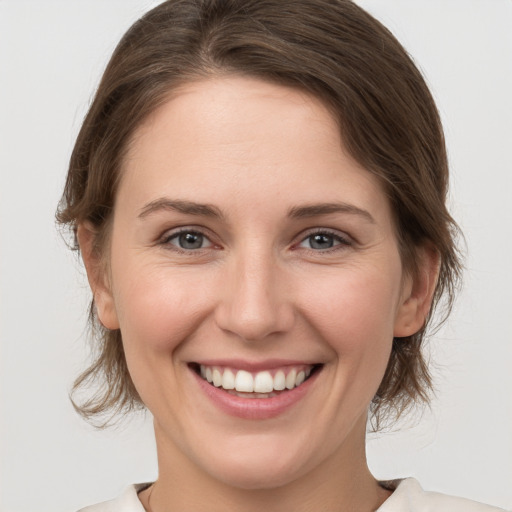 Joyful white young-adult female with medium  brown hair and grey eyes