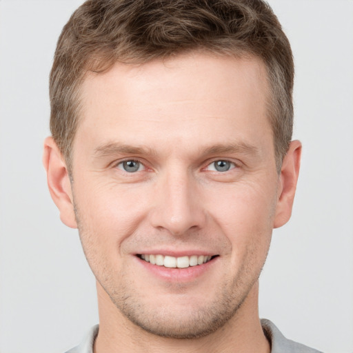 Joyful white young-adult male with short  brown hair and grey eyes