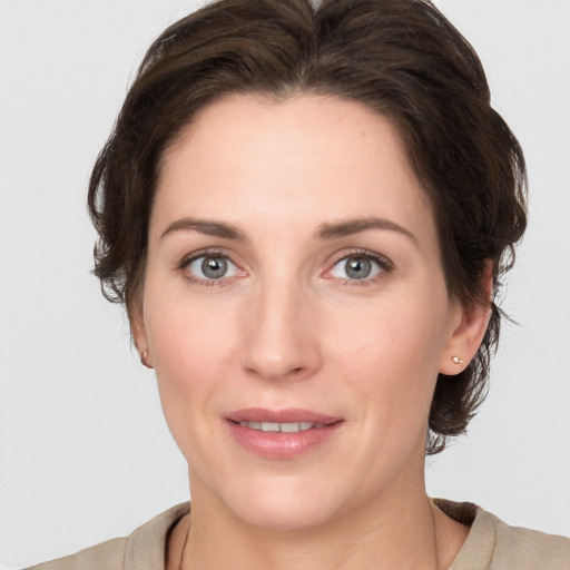 Joyful white young-adult female with medium  brown hair and grey eyes