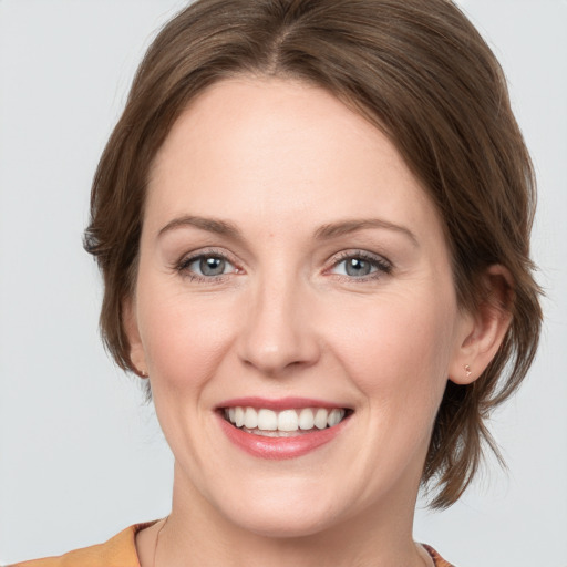 Joyful white young-adult female with medium  brown hair and grey eyes