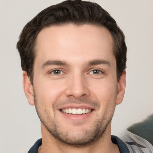 Joyful white young-adult male with short  brown hair and grey eyes