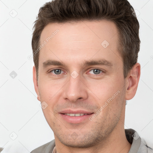 Joyful white young-adult male with short  brown hair and grey eyes