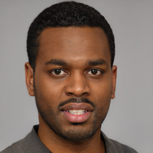 Joyful black young-adult male with short  black hair and brown eyes