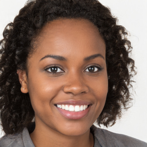 Joyful black young-adult female with long  brown hair and brown eyes