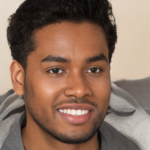 Joyful black young-adult male with short  brown hair and brown eyes