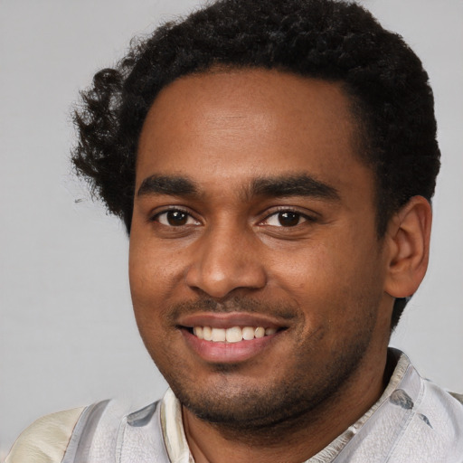 Joyful black young-adult male with short  brown hair and brown eyes