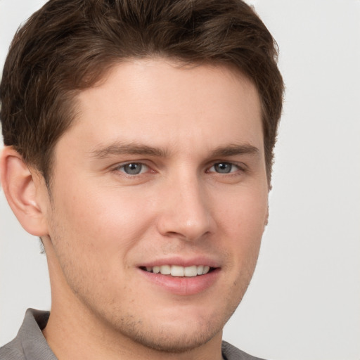 Joyful white young-adult male with short  brown hair and grey eyes