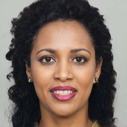 Joyful black young-adult female with long  black hair and brown eyes
