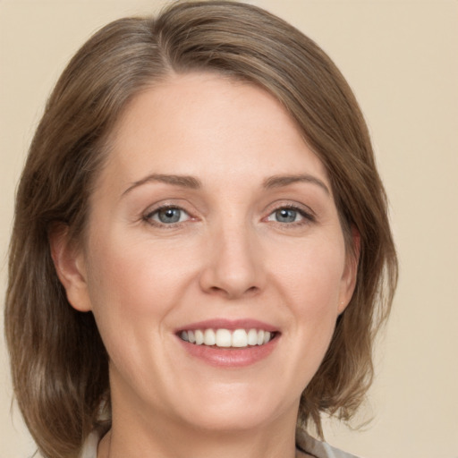 Joyful white adult female with medium  brown hair and grey eyes