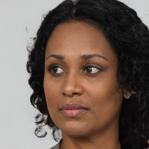 Joyful black adult female with long  black hair and brown eyes