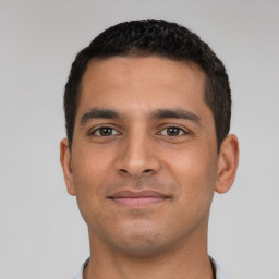 Joyful latino young-adult male with short  black hair and brown eyes