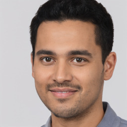 Joyful latino young-adult male with short  black hair and brown eyes