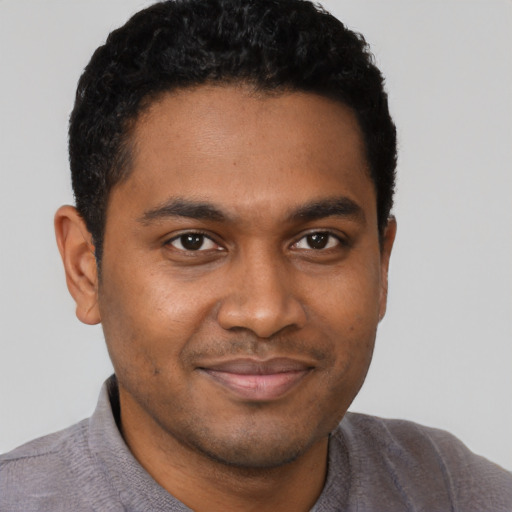 Joyful black young-adult male with short  brown hair and brown eyes