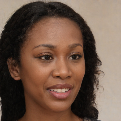Joyful black young-adult female with long  brown hair and brown eyes